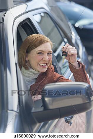 Stock Photo - Woman sitting in new car showing car key. Fotosearch
