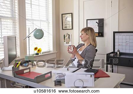 Woman sitting in office room, holding cup of tea View Large Photo Image Stock Photograph - Woman sitting in office room, holding cup of tea. Fotosearch