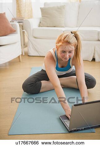 Stock Photograph - Woman sitting on floor and using laptop. Fotosearch