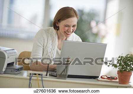 Stock Photograph - Woman working on laptop at home office. Fotosearch