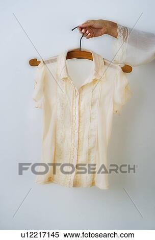 Stock Photography - Woman's hand holding coathanger with blouse. Fotosearch