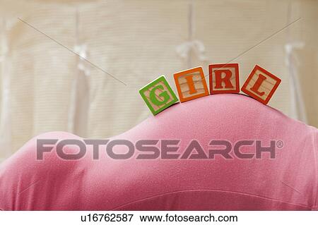 Stock Photo - Wooden blocks with letters on pregnant woman's belly, reading as girl. Fotosearch