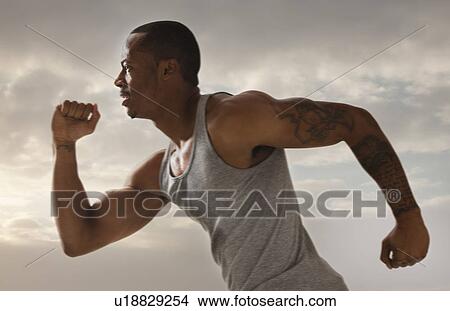 Young man running, cloudy sky in background View Large Photo Image Picture - Young man running, cloudy sky in background. Fotosearch