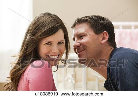 Stock Photo - Young pregnant woman about to be kissed by mid adult man. Fotosearch