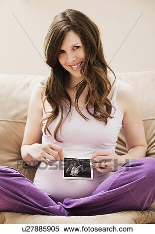 Stock Photography - Young pregnant woman holding CT image of unborn baby. Fotosearch