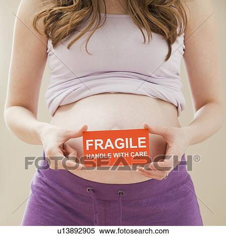Young pregnant woman holding fragile sign View Large Photo Image Stock Photography - Young pregnant woman holding fragile sign. Fotosearch