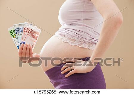 Stock Photography - Young pregnant woman holding money roll of Euros. Fotosearch