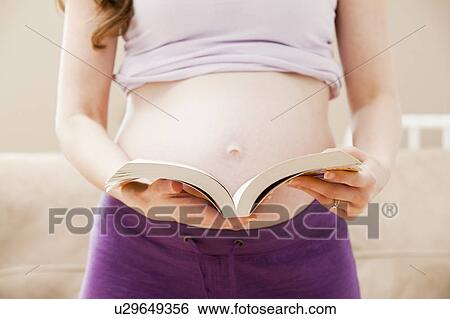 Stock Photograph - Young pregnant woman holding open book. Fotosearch