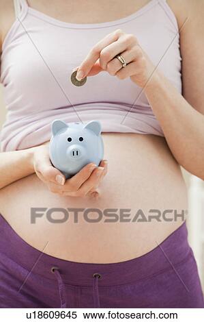 Young pregnant woman putting coin into blue piggybank View Large Photo Image Stock Photography - Young pregnant woman putting coin into blue piggybank. Fotosearch