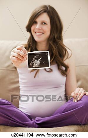 Picture - Young pregnant woman showing CT image of unborn baby. Fotosearch