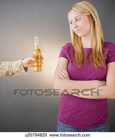 Stock Photo - Young woman being offered beer. Fotosearch