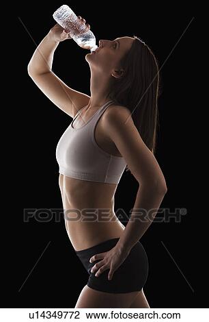 Young woman drinking water from bottle View Large Photo Image Stock Image - Young woman drinking water from bottle. Fotosearch