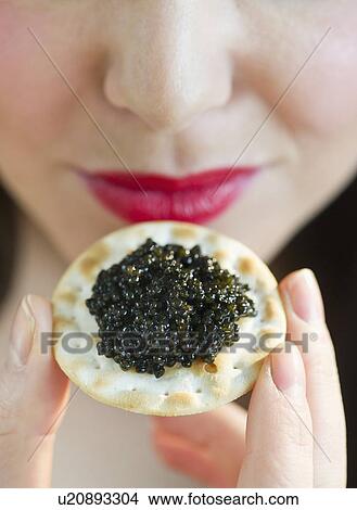 Picture - Young woman eating caviar snack, close-up of lips. Fotosearch