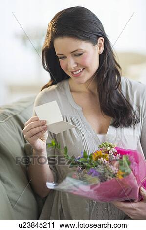 Young woman holding bouquet and reading greeting card View Large Photo Image Stock Image - Young woman holding bouquet and reading greeting card. Fotosearch