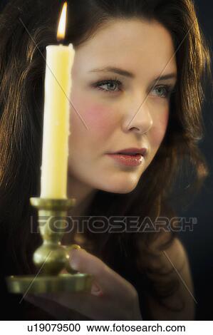 Stock Image - Young woman holding candle. Fotosearch