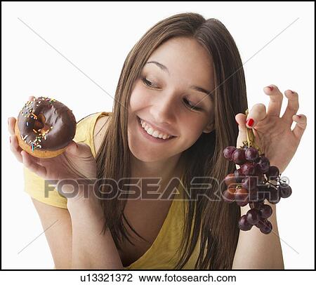 Young woman holding grapes and doughnut View Large Photo Image Stock Image - Young woman holding grapes and doughnut. Fotosearch