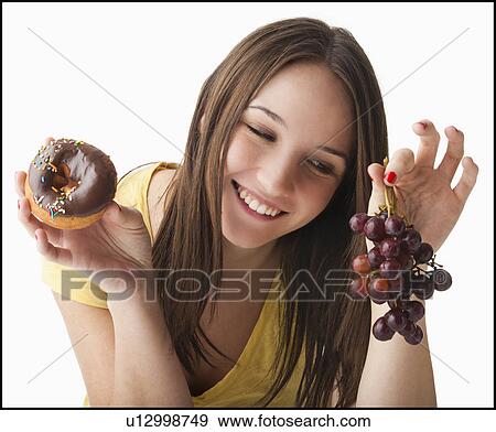 Young woman holding grapes and doughnut View Large Photo Image Stock Photo - Young woman holding grapes and doughnut. Fotosearch