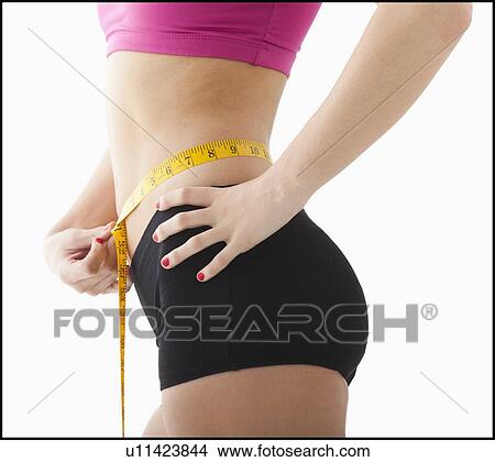 Picture - Young woman measuring waist. Fotosearch