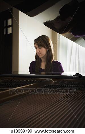 Stock Photo - Young woman playing grand piano. Fotosearch