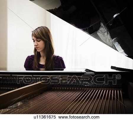 Stock Photography - Young woman playing grand piano. Fotosearch