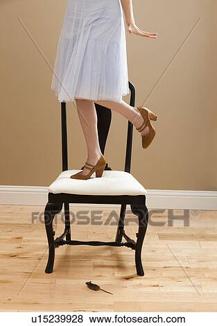 Young woman standing on chair, evading mouse View Large Photo Image Stock Photo - Young woman standing on chair, evading mouse. Fotosearch