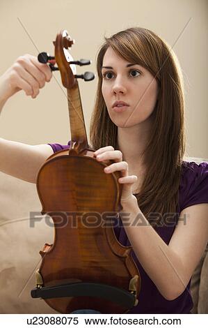 Stock Photography - Young woman tuning violin. Fotosearch