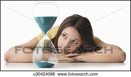 Young woman watching hourglass View Large Photo Image Stock Photo - Young woman watching hourglass. Fotosearch