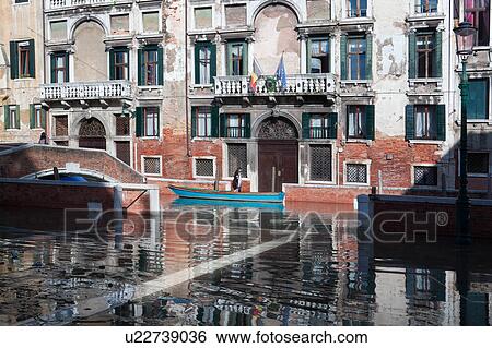 Aqua Alta flooding in Piazza Carmini: reflection of palazzo buildings reflected in flood water, pedestrian wading barefoot, carrying shoes, single wooden boat moored beside red brick bridge with another pedestrian crossing, sunny autumn morning in Venice, View Large Photo Image Stock Photograph - Aqua Alta flooding in Piazza Carmini: reflection of palazzo buildings reflected in flood water, pedestrian wading barefoot, carrying shoes, single wooden boat moored beside red brick bridge with another pedestrian crossing, sunny autumn morning in Venice,. Fotosearch