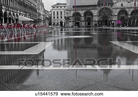 Aqua Alta flooding in Piazza San Marco: desaturated image highlighting empty red chairs, grey facade and loggia of the Procuratie, and Basilica of San Marco, Motion blur of single pedestrian in purple, reflected in the water, Venice, Northern Italy View Large Photo Image Stock Photo - Aqua Alta flooding in Piazza San Marco: desaturated image highlighting empty red chairs, grey facade and loggia of the Procuratie, and Basilica of San Marco, Motion blur of single pedestrian in purple, reflected in the water, Venice, Northern Italy. Fotosearch