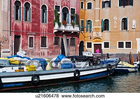 Bright blue and white laden barge moored in front of red and yellow palazzi, with single woman in pink walking alongside canal, sunny autumn morning in Venice, Northern Italy View Large Photo Image Stock Photo - Bright blue and white laden barge moored in front of red and yellow palazzi, with single woman in pink walking alongside canal, sunny autumn morning in Venice, Northern Italy. Fotosearch