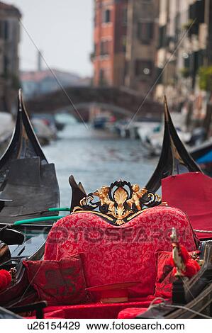 Close up of two gondolas, showing red cushions and seating, gilt and black decorations against background of canal and bridges leading to Giudecca, sunny autumn morning in Venice, Northern Italy View Large Photo Image Stock Photo - Close up of two gondolas, showing red cushions and seating, gilt and black decorations against background of canal and bridges leading to Giudecca, sunny autumn morning in Venice, Northern Italy. Fotosearch