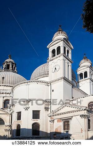 Detail of church of Santa Maria della Salute: dome with ornamental stone scroll work and statues below, bell and clock towers, against deep blue sky, late afternoon in autumn, Venice, Northern Italy View Large Photo Image Stock Photography - Detail of church of Santa Maria della Salute: dome with ornamental stone scroll work and statues below, bell and clock towers, against deep blue sky, late afternoon in autumn, Venice, Northern Italy. Fotosearch