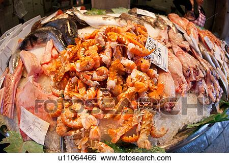 Stock Photograph - Fish market at Rialto Bridge: close up of display, with motion blur of vendor wearing red checked overalls in background, Venice, Northern Italy. Fotosearch
