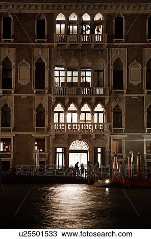 Night view of Grand Canal with Palazzo illuminated at dusk, silhouetted couple in brightly lit foyer talking to gondolier in striped shirt, autumn in Venice, Northern Italy View Large Photo Image Stock Image - Night view of Grand Canal with Palazzo illuminated at dusk, silhouetted couple in brightly lit foyer talking to gondolier in striped shirt, autumn in Venice, Northern Italy. Fotosearch