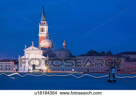 View of church of San Giorgio Maggiore at twilight, with multiple multicoloured wavy lines from motion blurs of boat lights, and water of Canale della Giudecca, lights illuminated along quayside, autumn in Venice, Northern Italy View Large Photo Image Picture - View of church of San Giorgio Maggiore at twilight, with multiple multicoloured wavy lines from motion blurs of boat lights, and water of Canale della Giudecca, lights illuminated along quayside, autumn in Venice, Northern Italy. Fotosearch