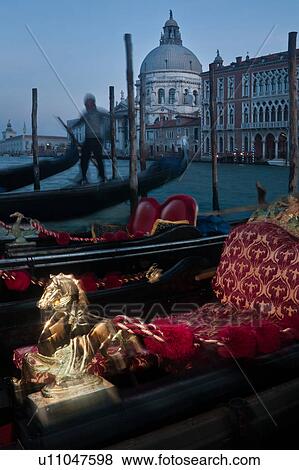 View of Grand Canal, with motion blur of gondolas with red cushion seating and golden hippocampus decoration in foreground, Gondolier in striped shirt beyond, Santa Maria della Salute church across canal, at dusk with illumination, autumn in Venice, North View Large Photo Image Stock Photo - View of Grand Canal, with motion blur of gondolas with red cushion seating and golden hippocampus decoration in foreground, Gondolier in striped shirt beyond, Santa Maria della Salute church across canal, at dusk with illumination, autumn in Venice, North. Fotosearch