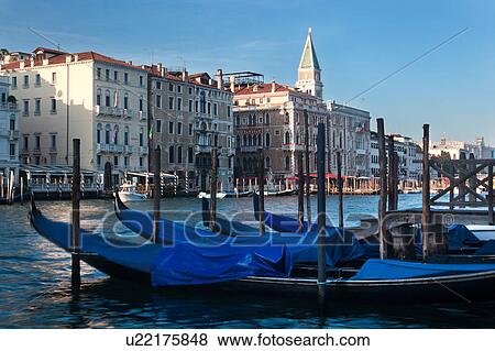 Stock Photo - View of Grand Canal, with motion blur of covered gondolas in foreground, palazzi and Campanile across canal, in late afternoon sun, autumn in Venice, Northern Italy. Fotosearch
