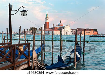 View of San Marco basin, looking past moored gondolas in foreground, motor boats in motion on water, to San Giorgio Maggiore church and nearby harbour, sunset, autumn in Venice, Northern Italy View Large Photo Image Picture - View of San Marco basin, looking past moored gondolas in foreground, motor boats in motion on water, to San Giorgio Maggiore church and nearby harbour, sunset, autumn in Venice, Northern Italy. Fotosearch