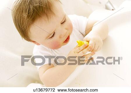 Stock Image - Baby boy eating a crisp. Fotosearch