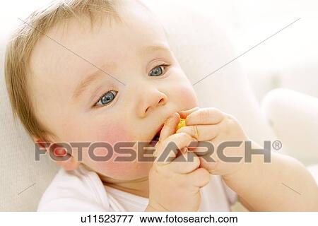 Stock Photo - Baby boy eating a crisp. Fotosearch