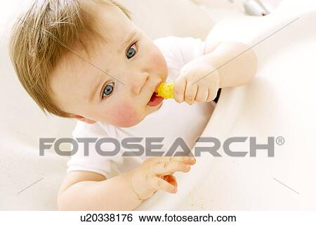 Stock Photograph - Baby boy eating a crisp. Fotosearch
