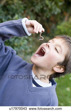 Stock Image - Boy pretending to eat an earthworm. Fotosearch