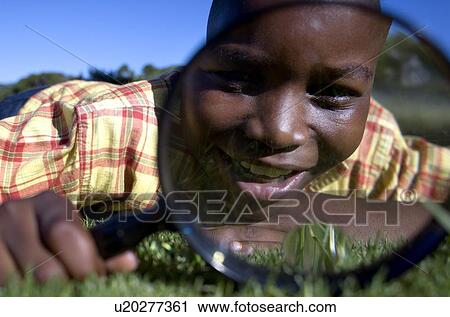 Stock Image - Boy using a magnifying glass. Fotosearch