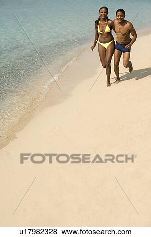 Couple jogging along a beach View Large Photo Image Stock Photo - Couple jogging along a beach. Fotosearch
