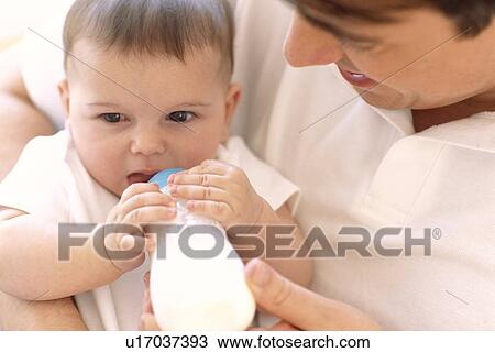 Stock Image - Father bottle-feeding baby girl. Fotosearch