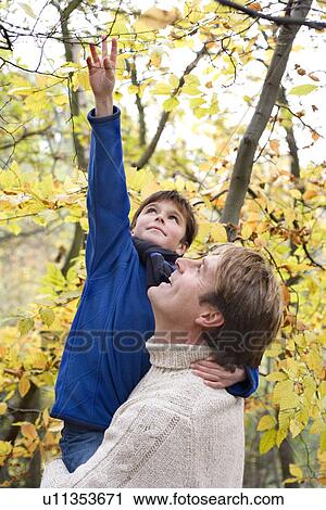 Stock Image - Father carrying his son in a wood. Fotosearch