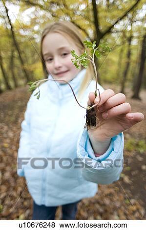 Stock Photo - Girl holding a plant seedling. Fotosearch
