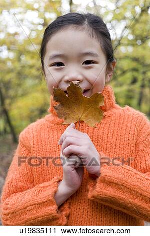 Stock Image - Girl holding an autumn leaf. Fotosearch