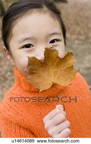 Girl holding an autumn leaf View Large Photo Image Stock Photo - Girl holding an autumn leaf. Fotosearch