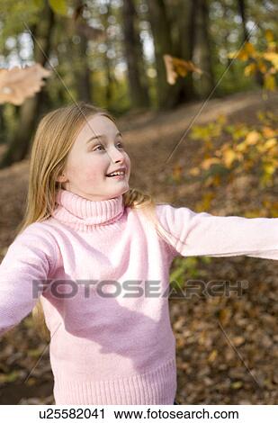 Stock Image - Girl playing with autumn leaves. Fotosearch